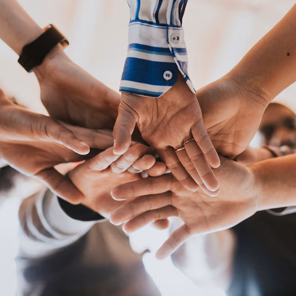 Multiple hands stacked together symbolizing teamwork and unity.