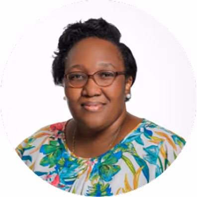 Portrait of a woman wearing glasses and a colorful floral blouse with a white background.
